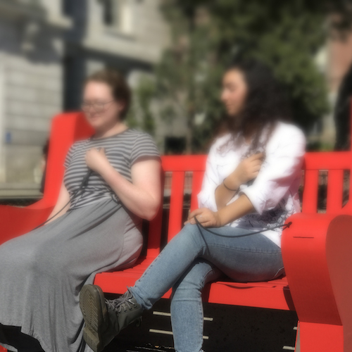 Two people sitting on the Heart Sounds Bench quietly listening to the live unfiltered sounds of their hearts blending together with the environment.